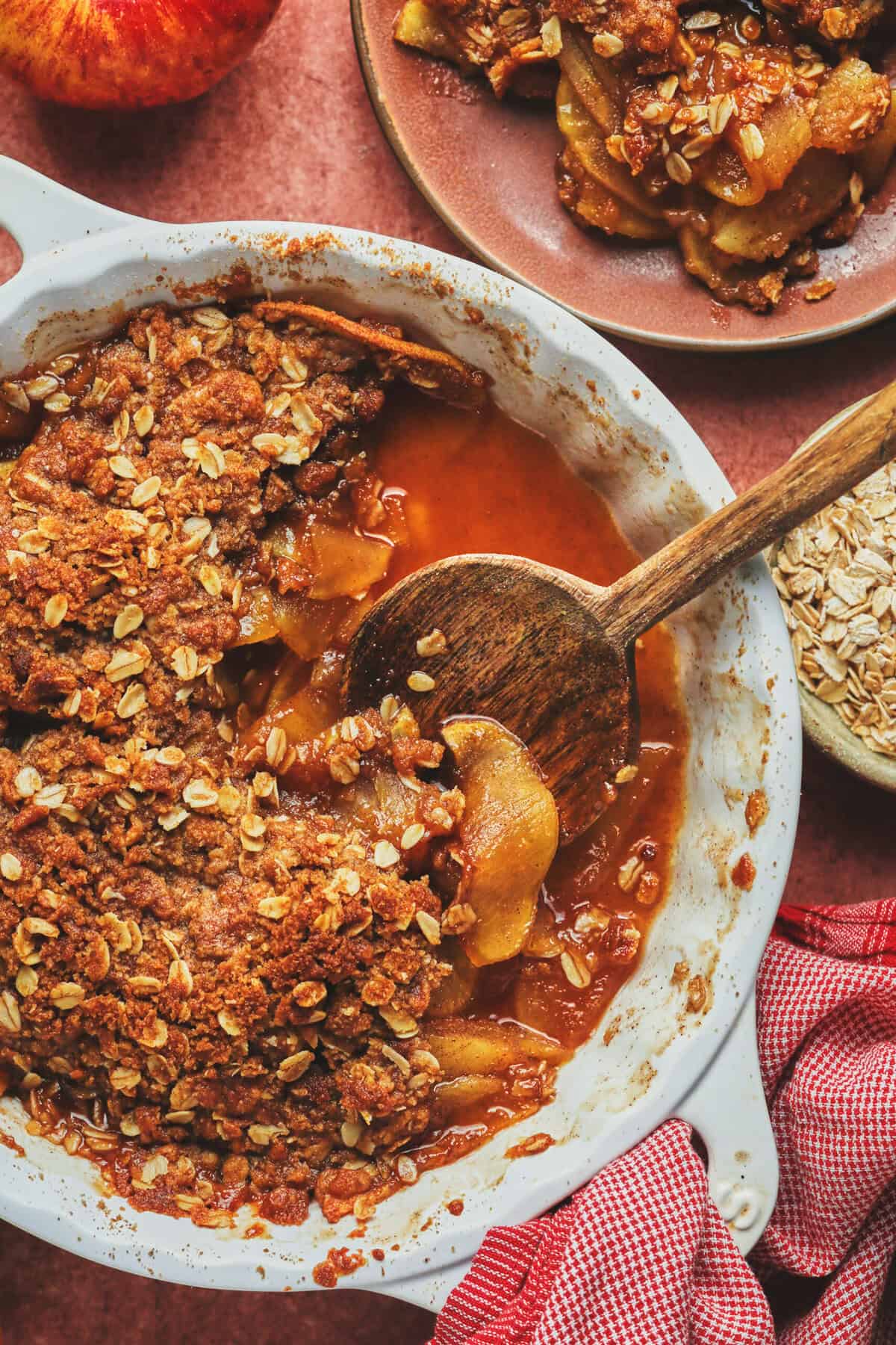 Overhead of apple crisp and a serving spoon in a serving dish with a scoop missing.
