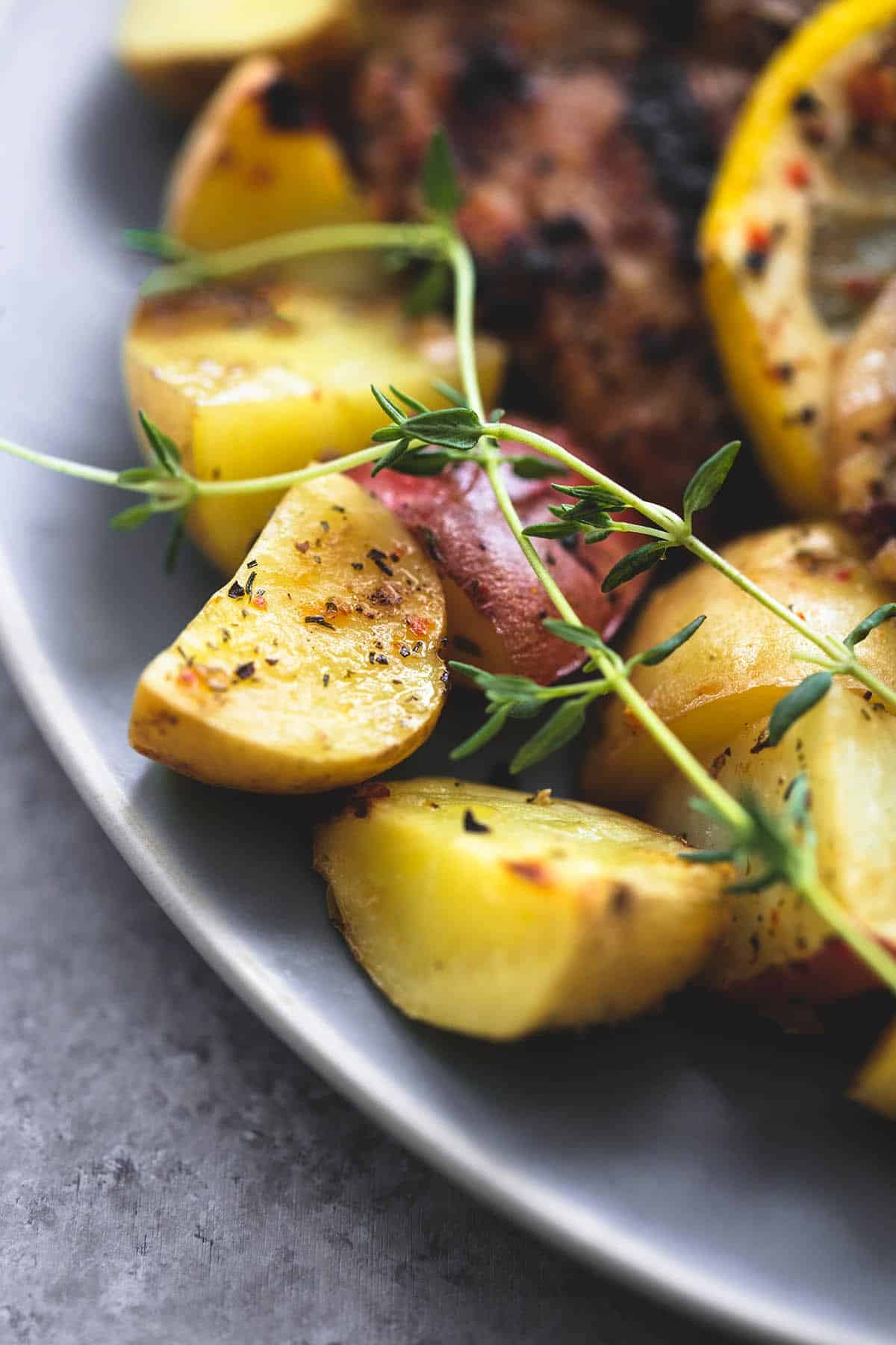 close up of baked lemon herb chicken & potatoes on a plate.