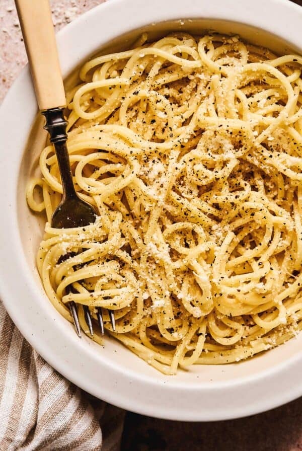 Close up overhead of cache e pepe pasta sauce on pasta with a fork in a pasta dish.