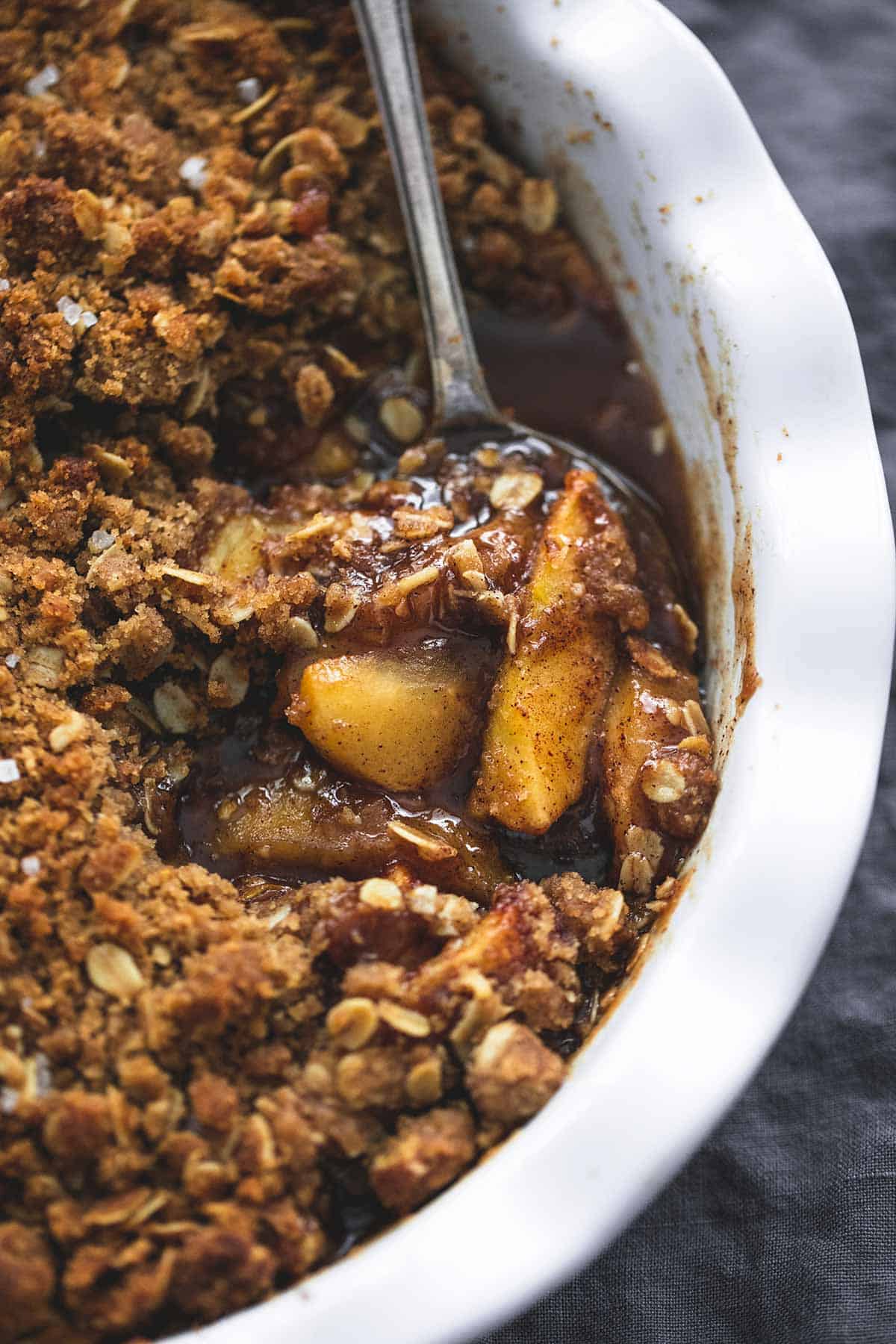 close up of apple crisp and a spoon in a serving bowl.