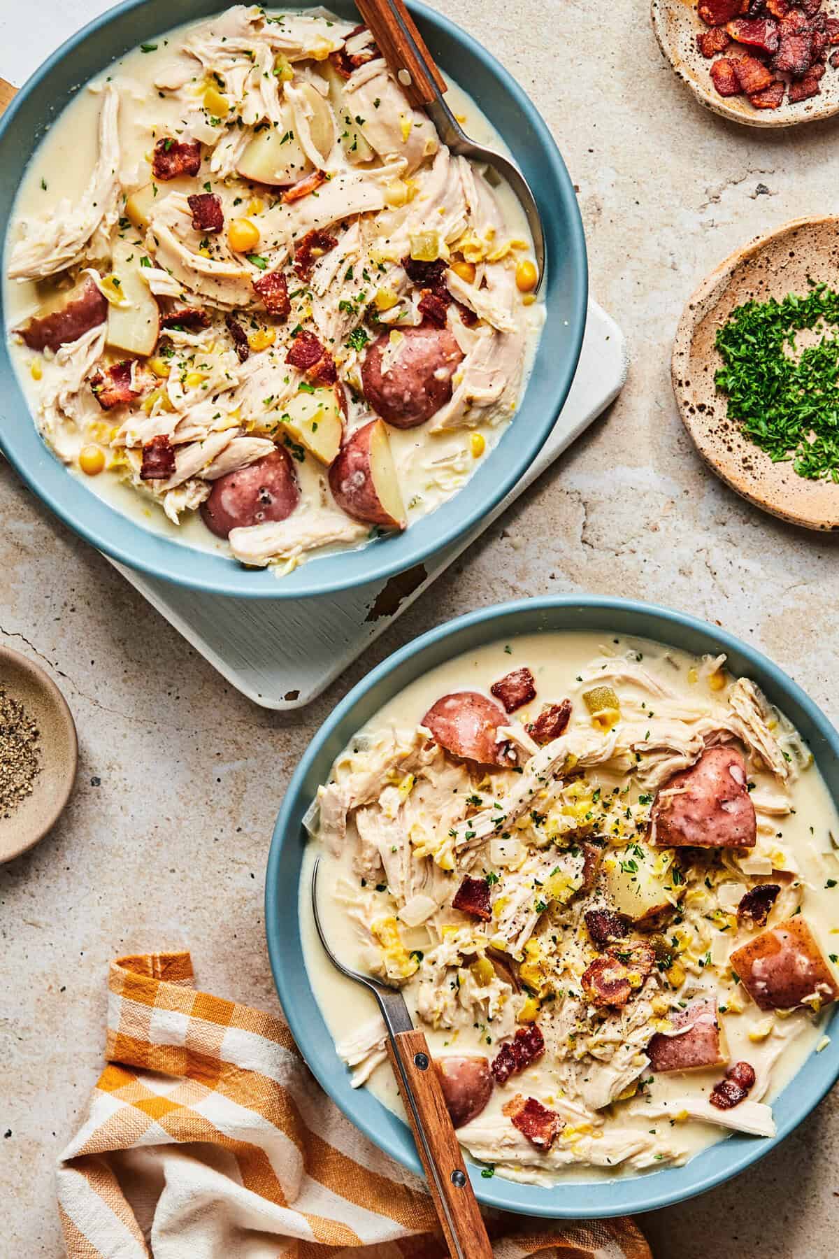 two bowls of chicken corn chowder with parsley on the side.