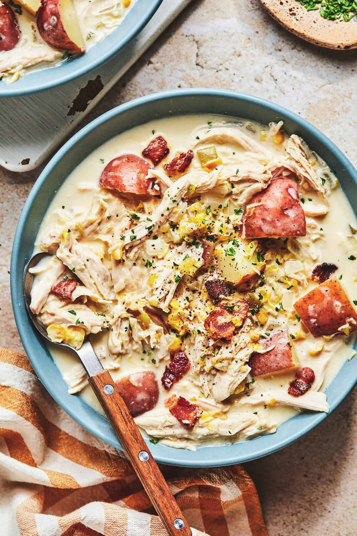 bowl of corn chowder with chicken and potatoes with checkered napkin.