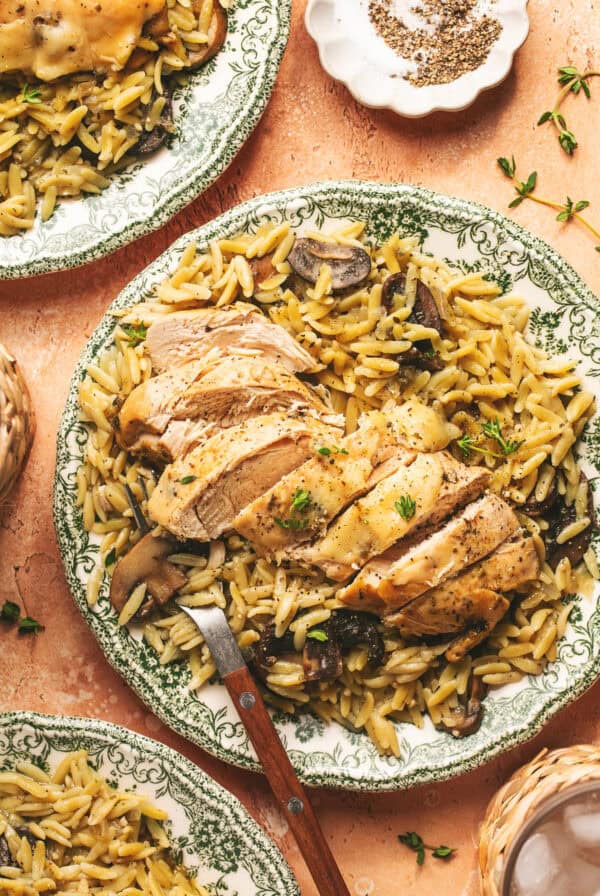 Overhead of sliced chicken on top of orzo with a fork on a plate.