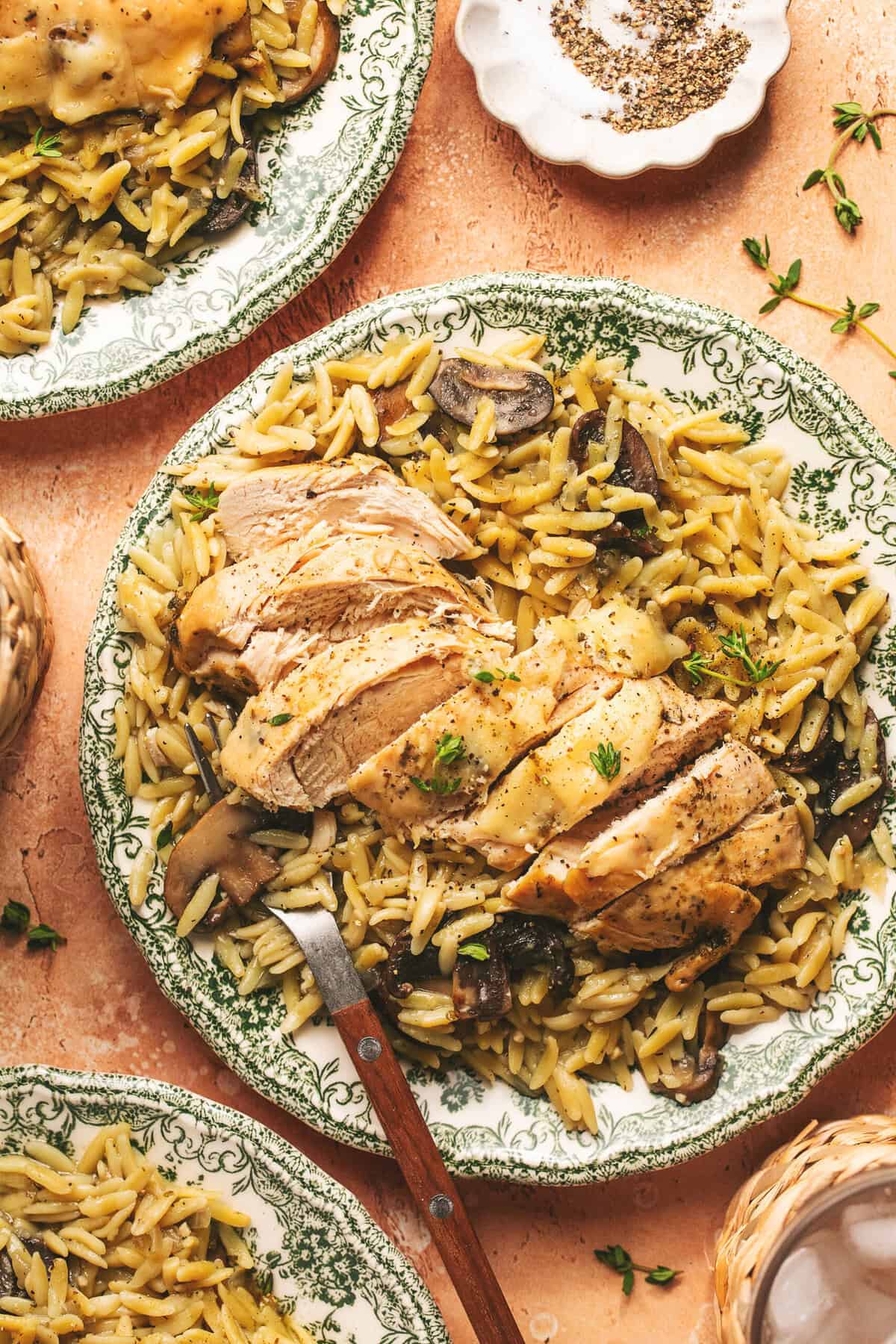 Overhead of sliced chicken on top of orzo with a fork on a plate. 