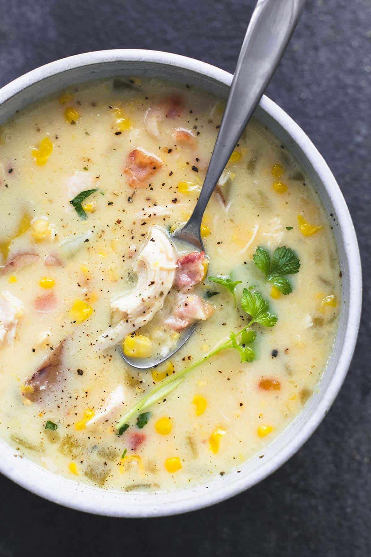 close up top view of slow cooker corn chowder with a spoon in a bowl.