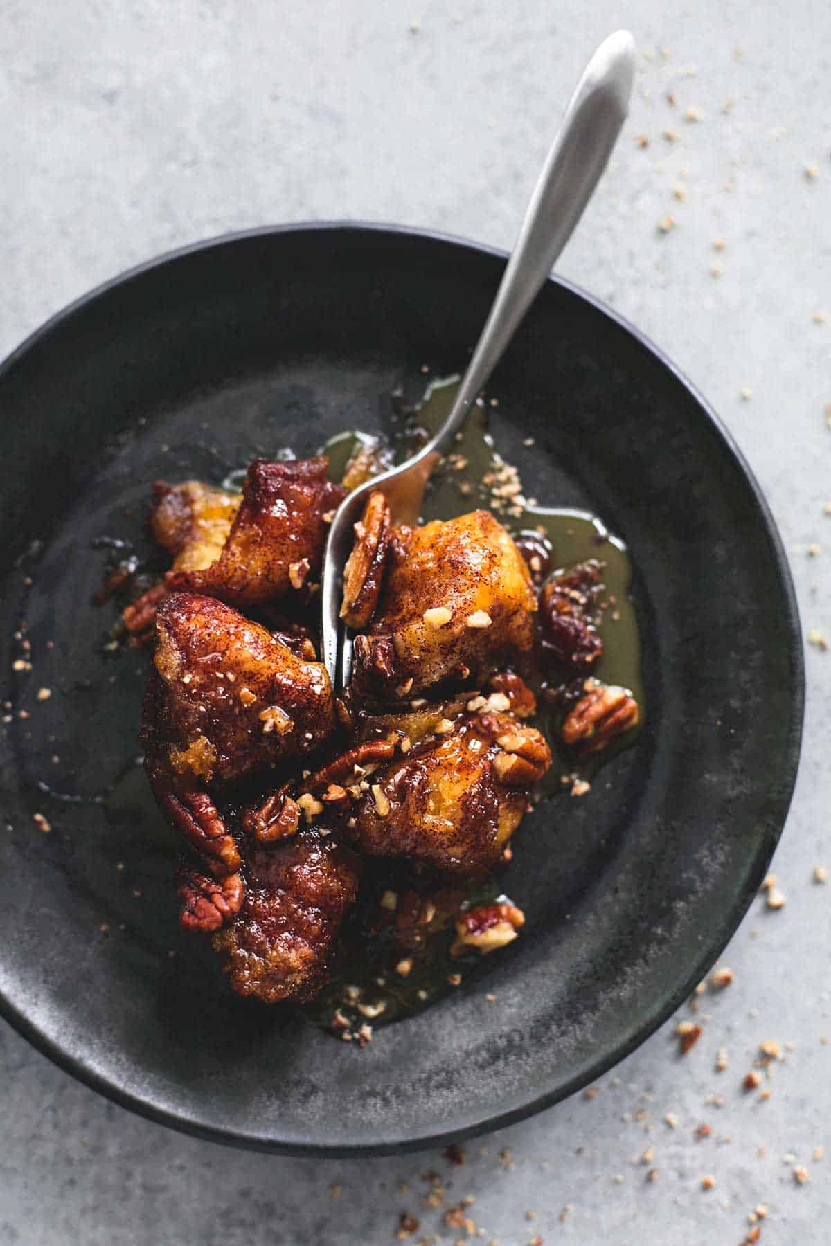 top view of a fork cutting into slow cooker caramel pecan monkey bread on a plate.