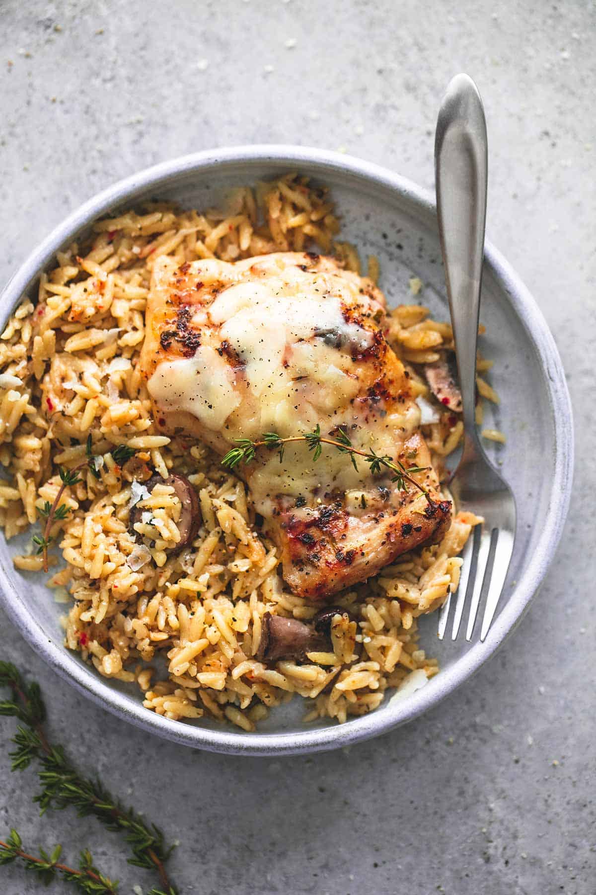 top view of slow cooker parmesan herb chicken & orzo with a fork on a plate.