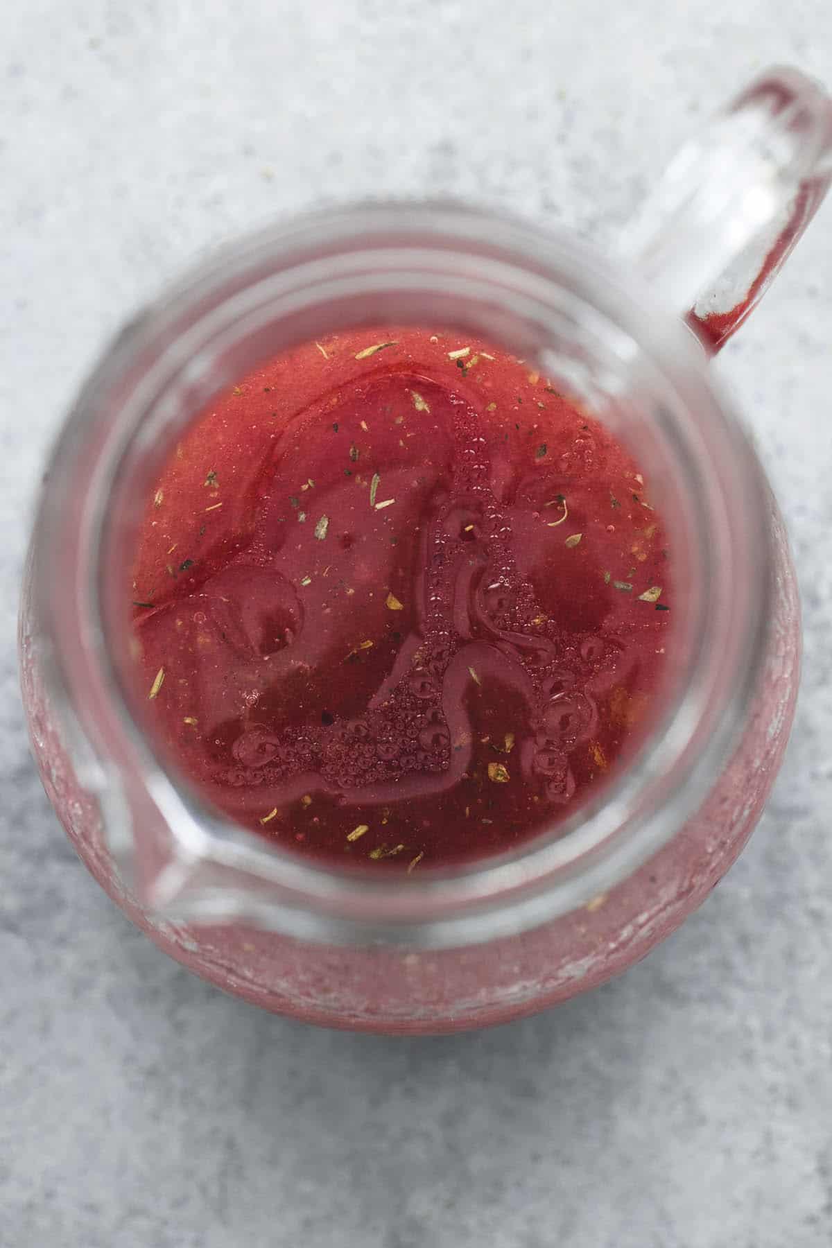 top view of sweet and tangy apple cranberry dressing in a small glass pitcher.