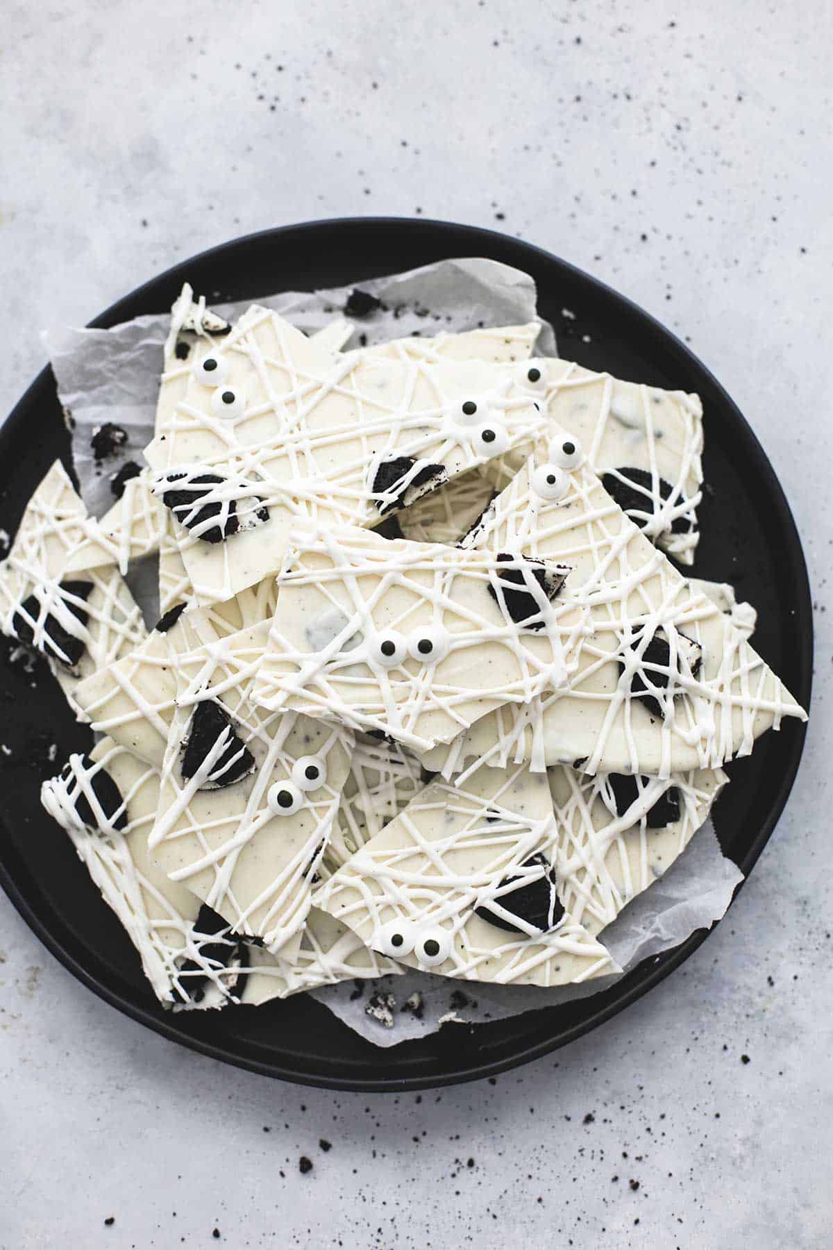 top view of a bunch of white chocolate mummy bark on a black plate. 