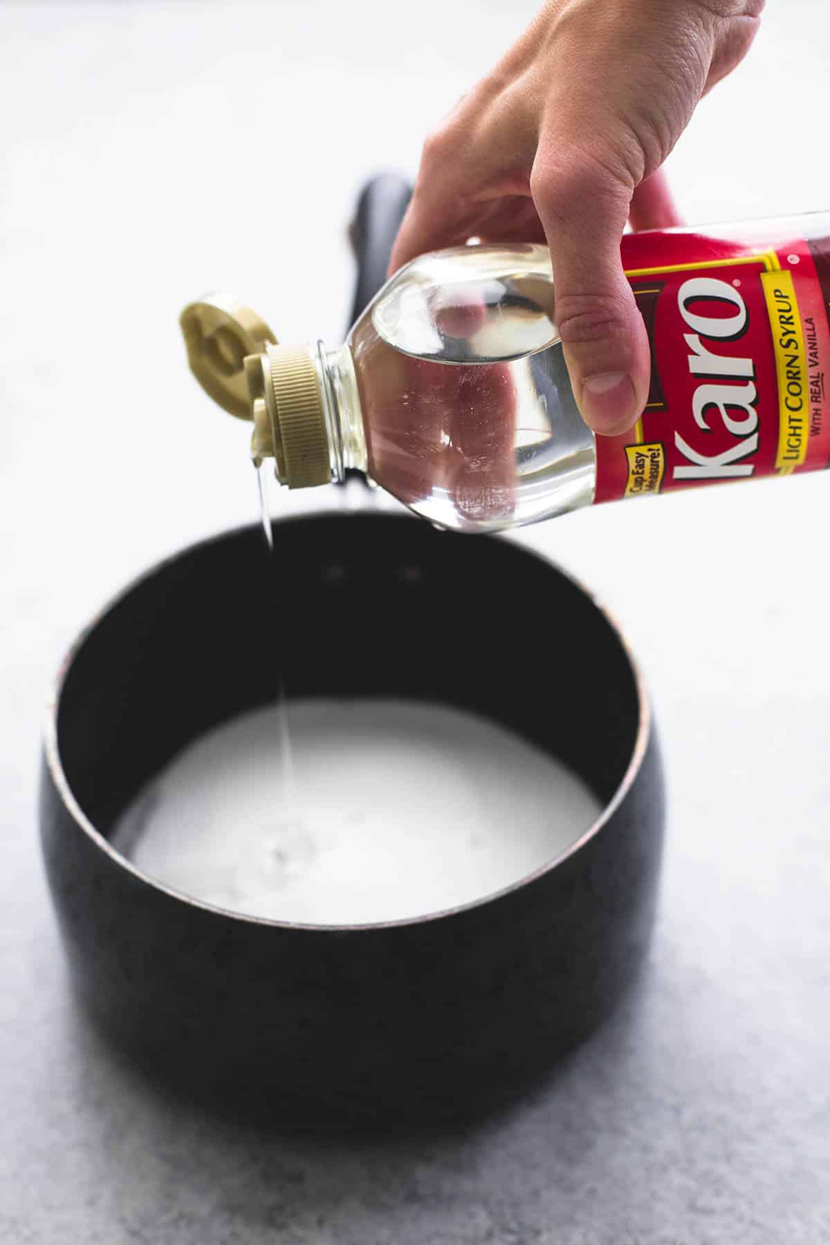 a hand pouring a bottle of Karo in a pan.
