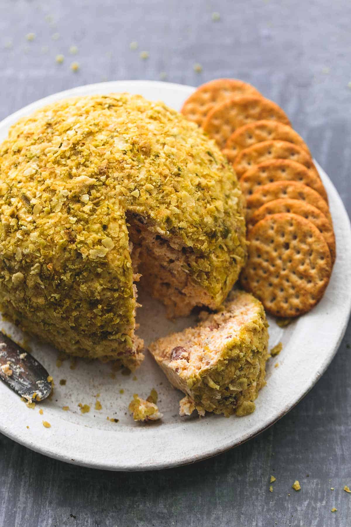 cheddar bacon jalapeno cheeseball with crackers on a plate.