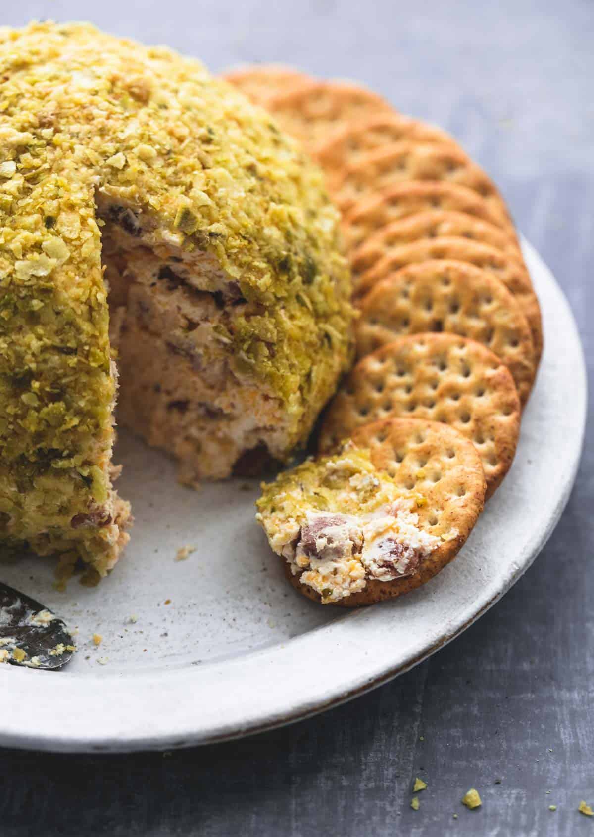 cheddar bacon jalapeno cheeseball with crackers with the front cracker having some of the cheeseball on it all on a plate.