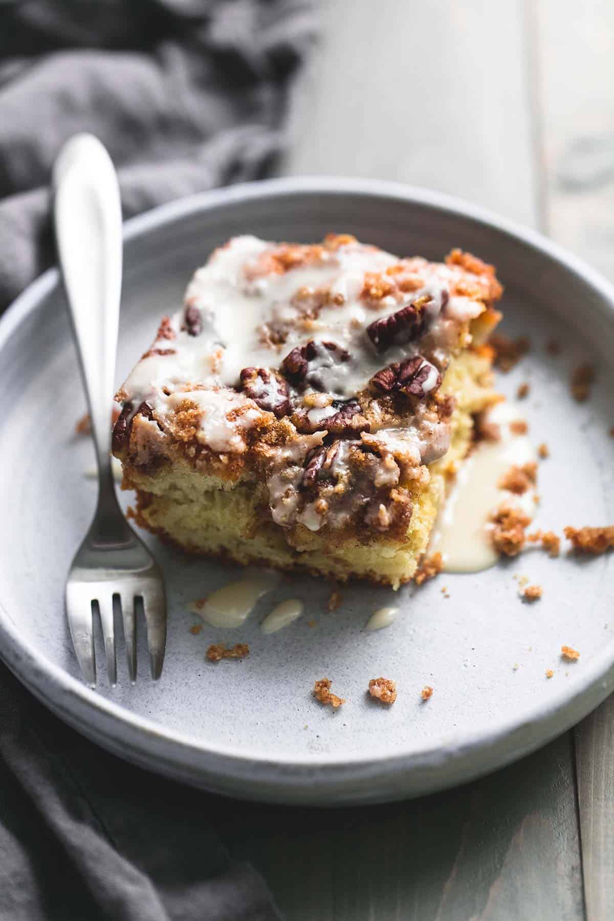 a piece of cinnamon pecan coffee cake with a fork on a plate.