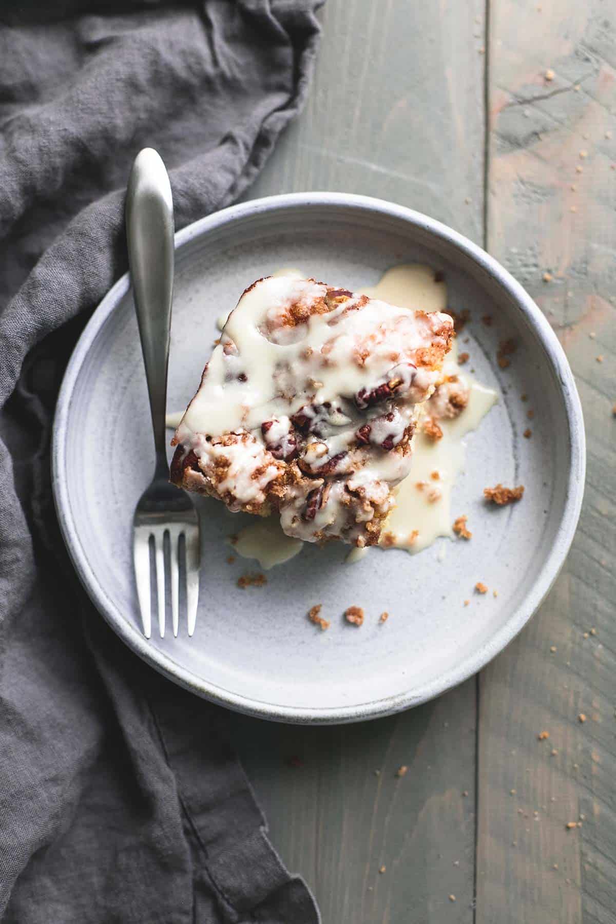 top view of a piece of cinnamon pecan coffee cake with a fork on a plate.