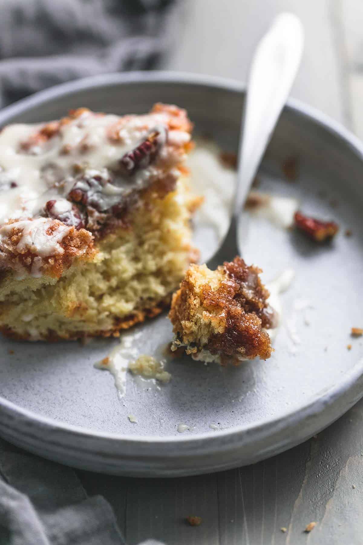 a piece of cinnamon pecan coffee cake with a bite on a fork on a plate.