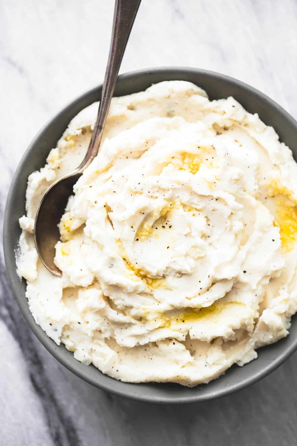 top view of garlic sour cream mashed potatoes and a spoon in a bowl.