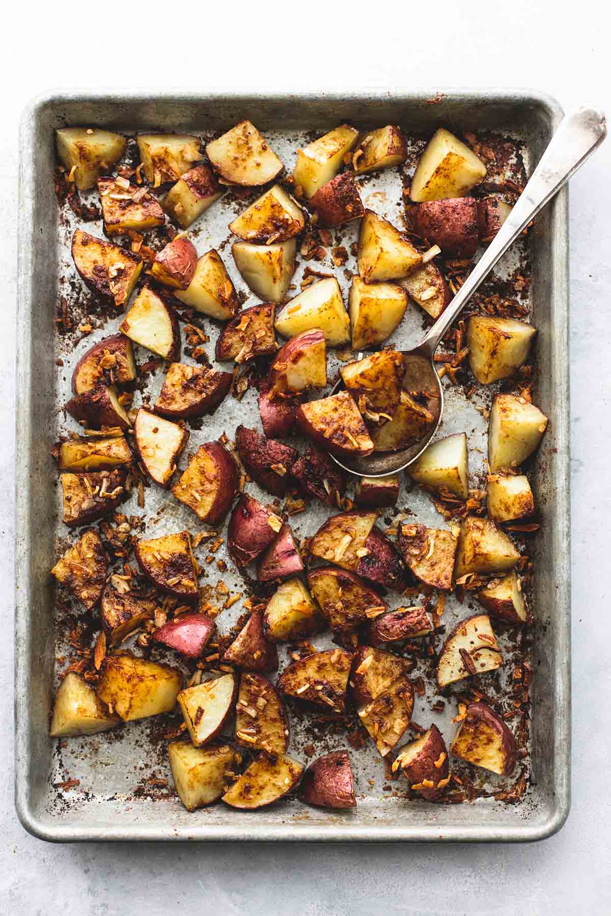 top view of oven roasted potatoes with a spoon on a baking sheet.