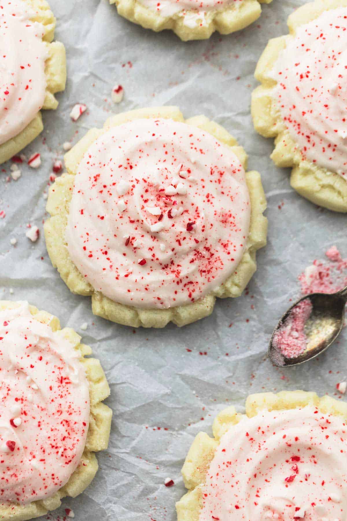 top view of a peppermint sugar cookie surrounded by more cookies with a spoon on the side.