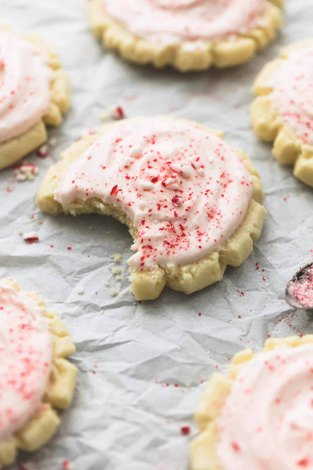 a peppermint sugar cookie with a bite missing with more cookies around it.