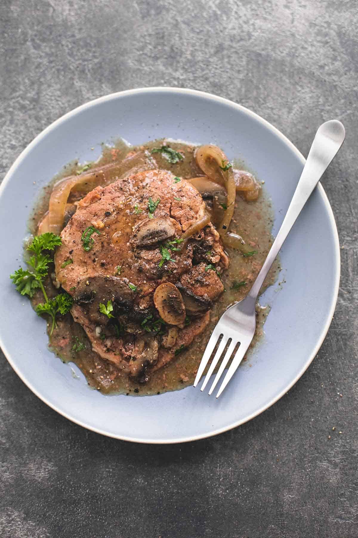 top view of slow cooker swiss steak with a fork on a plate.