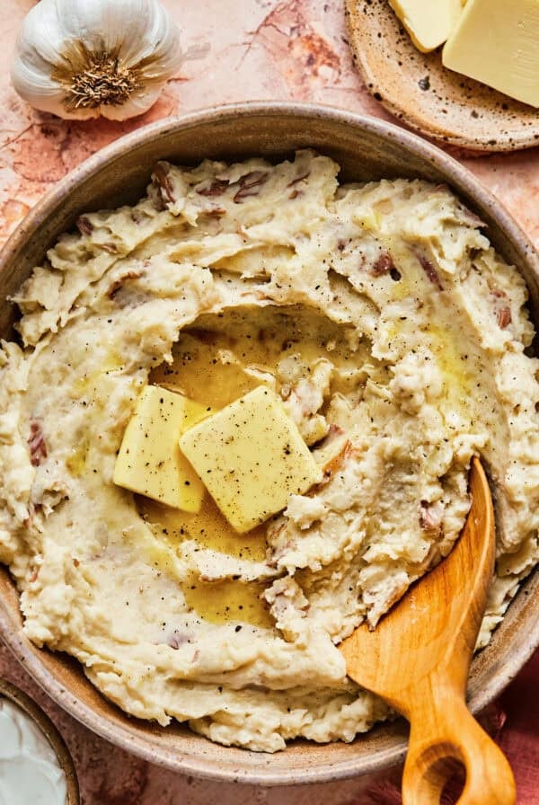 Overhead of garlic sour cream mashed potatoes in a ceramic serving bowl.