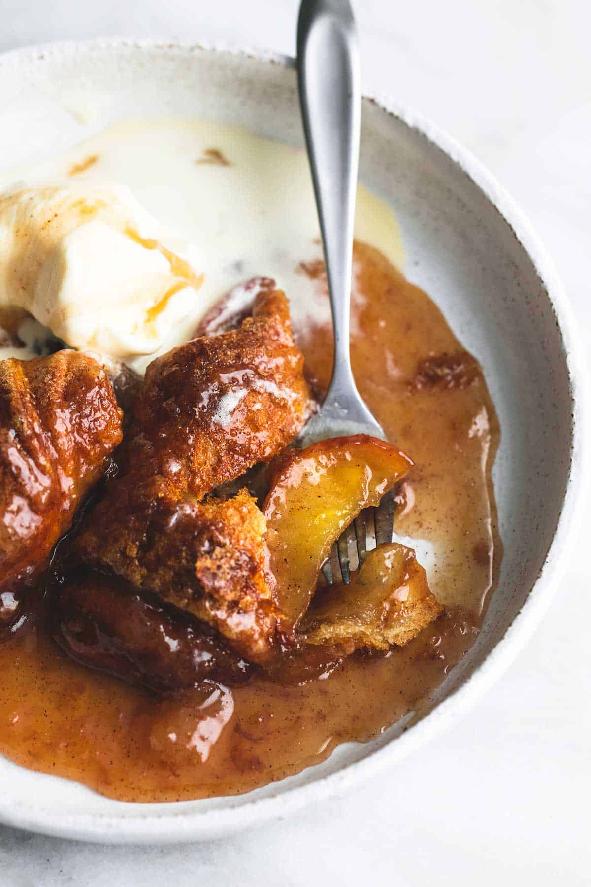 This simple 7UP apple cobbler is made with refrigerated crescent dough and a cinnamon sugar and 7UP caramel sauce that is to die for. | lecremedelacrumb.com close up top view of apple cobbler with a fork on a plate.