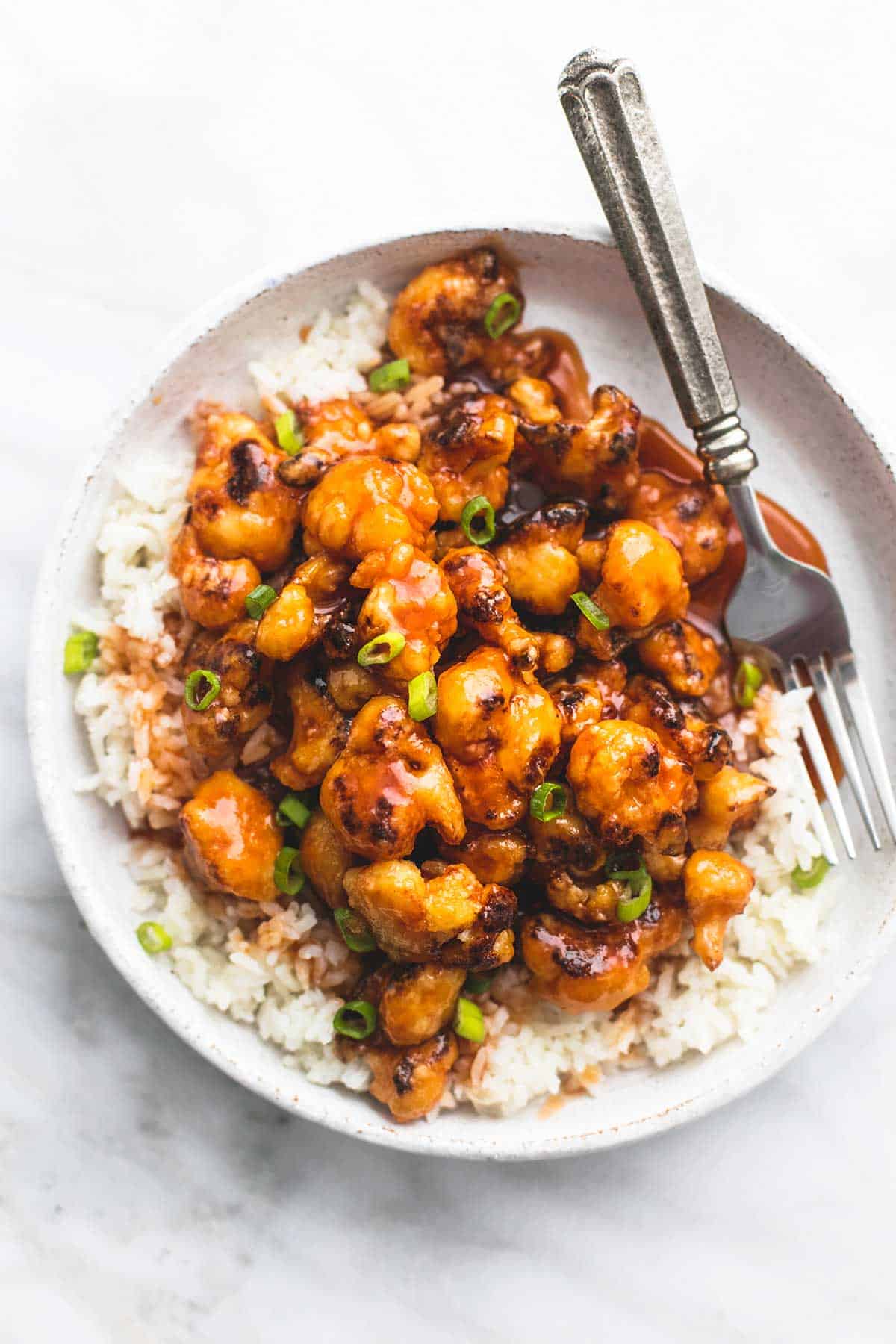 top view of baked sweet & sour cauliflower with fork on a plate.