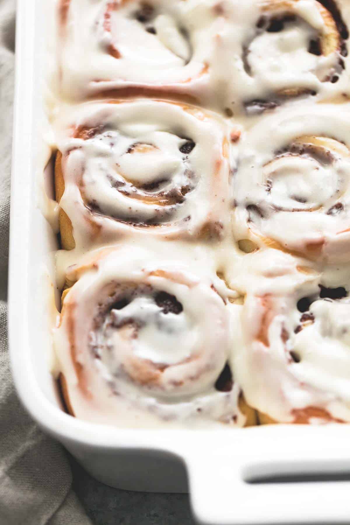 close up of cream cheese cinnamon rolls in a baking pan.