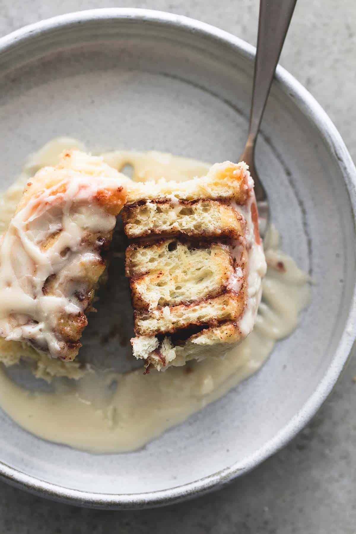 top view of a cream cheese cinnamon roll split in half with a fork on a plate.