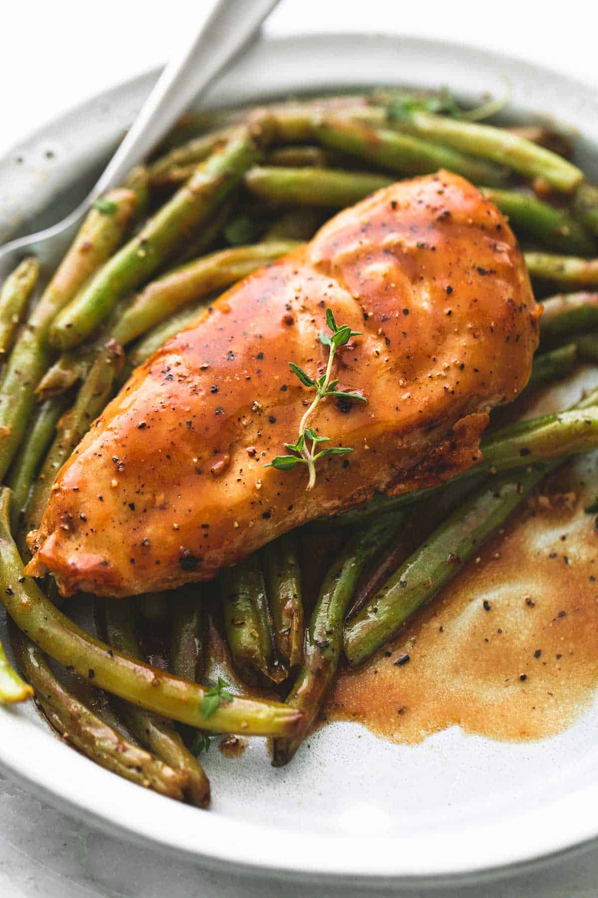 close up of creamy balsamic chicken & green beans with a fork on a plate.