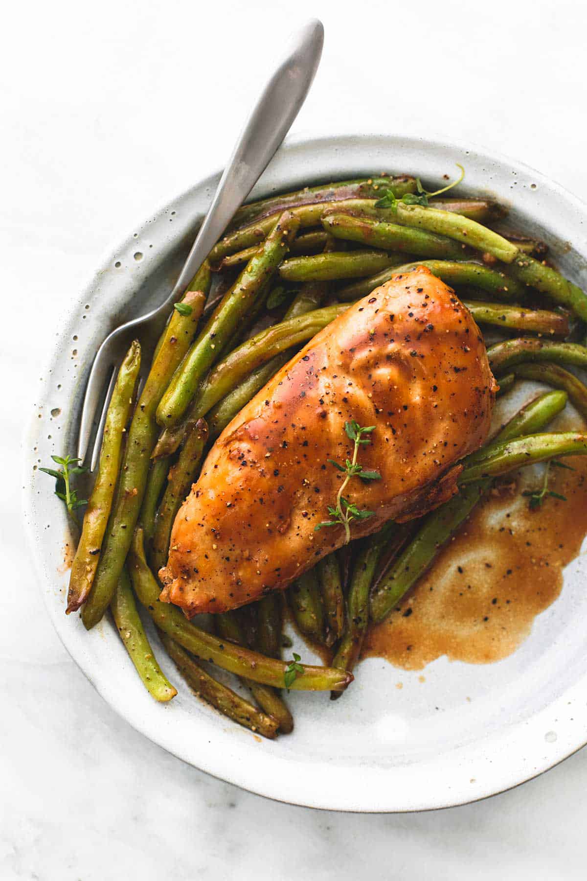 top view of creamy balsamic chicken & green beans with a fork on a plate.