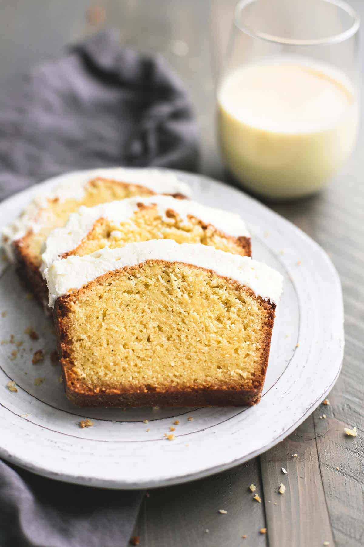 eggnog pound cake slices on a cake with a glass of eggnog on the side.