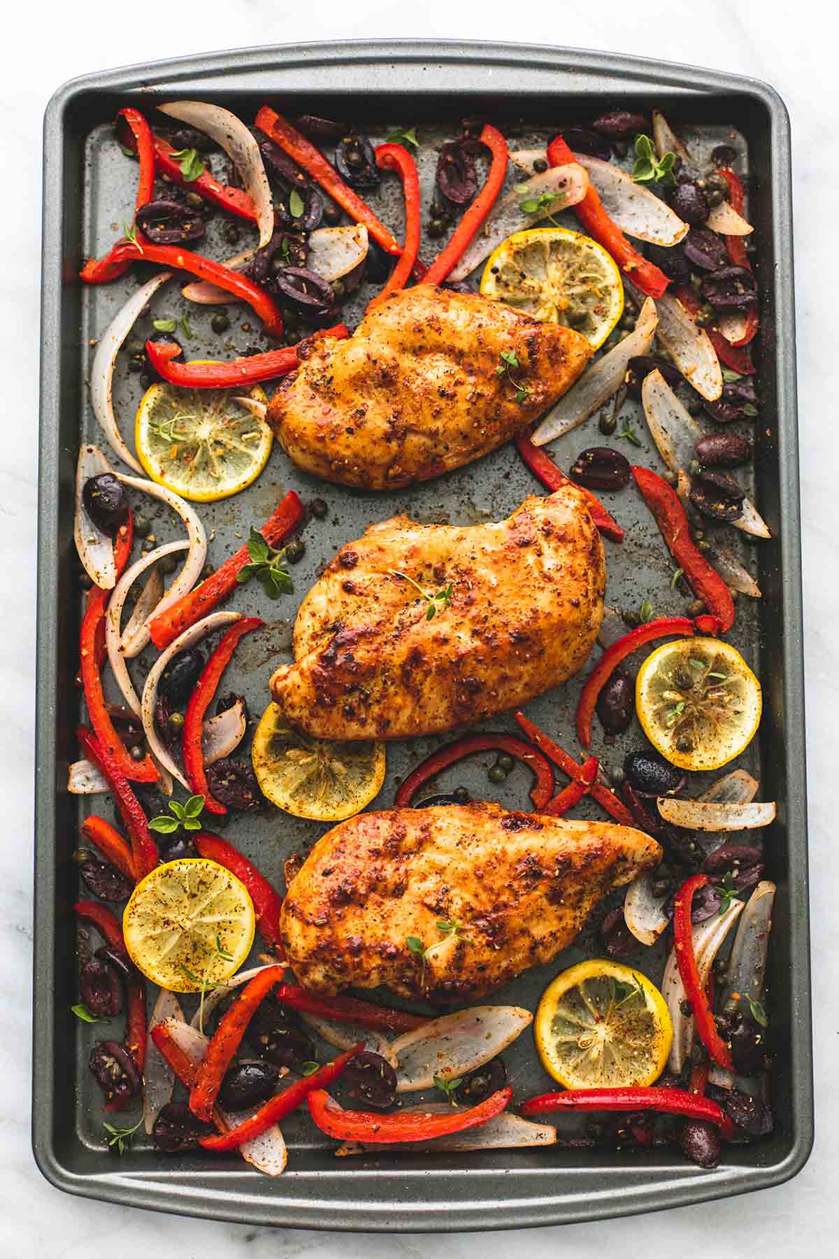 top view of baked Greek chicken sheet pan dinner on a baking sheet.