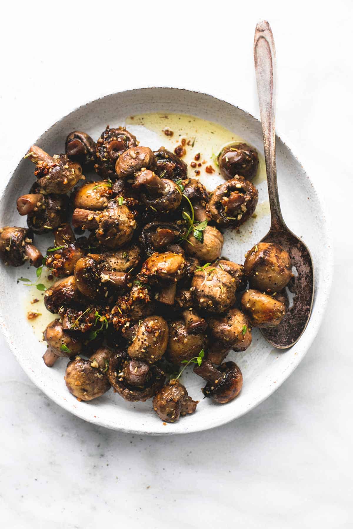 top view of sautéed garlic butter mushrooms and a spoon on a plate.