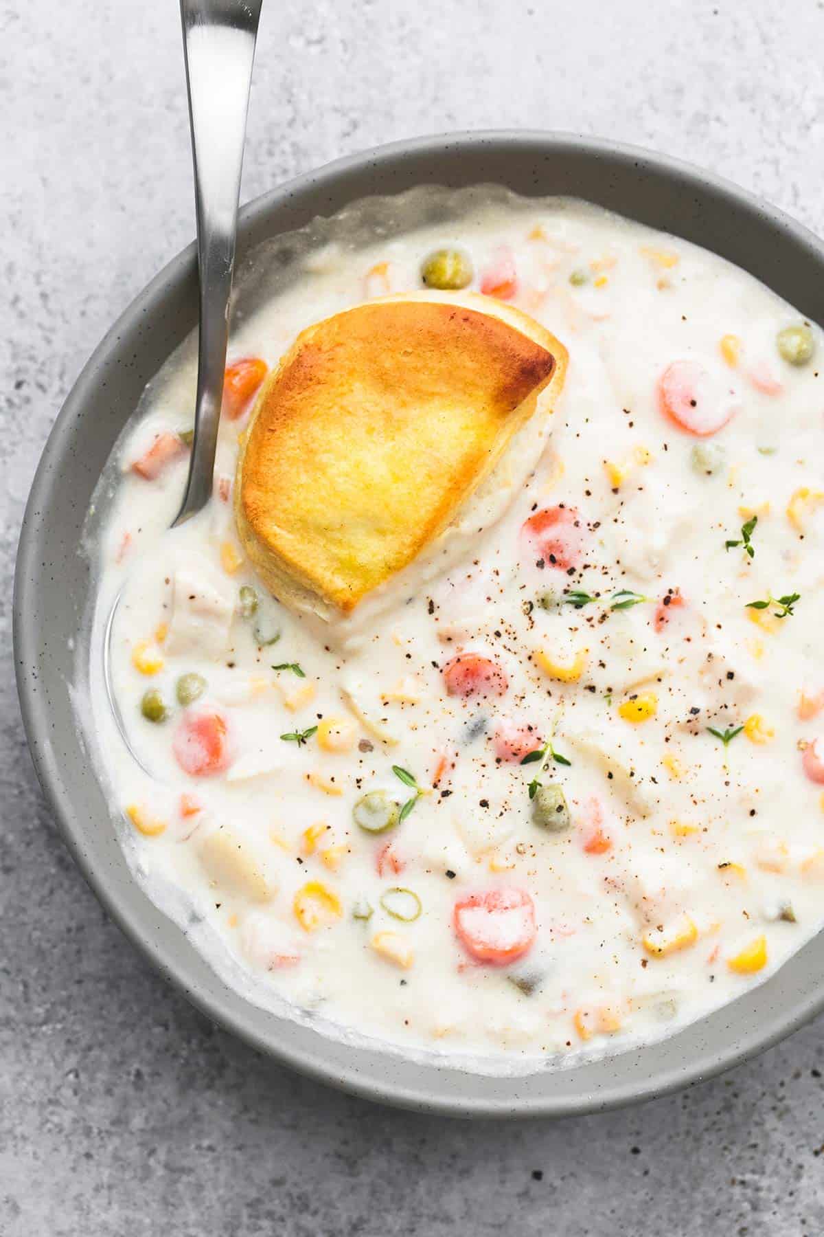 top view of slow cooker chicken pot pie soup with a biscuit and a spoon in a bowl.