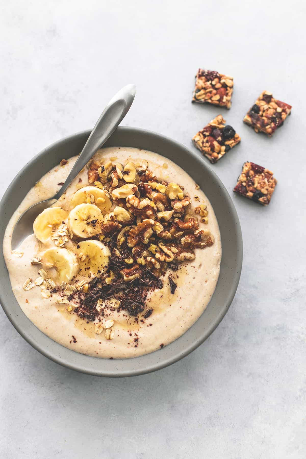top view of a banana nut smoothie bowl with a spoon in it and granola bar chunks on the side.