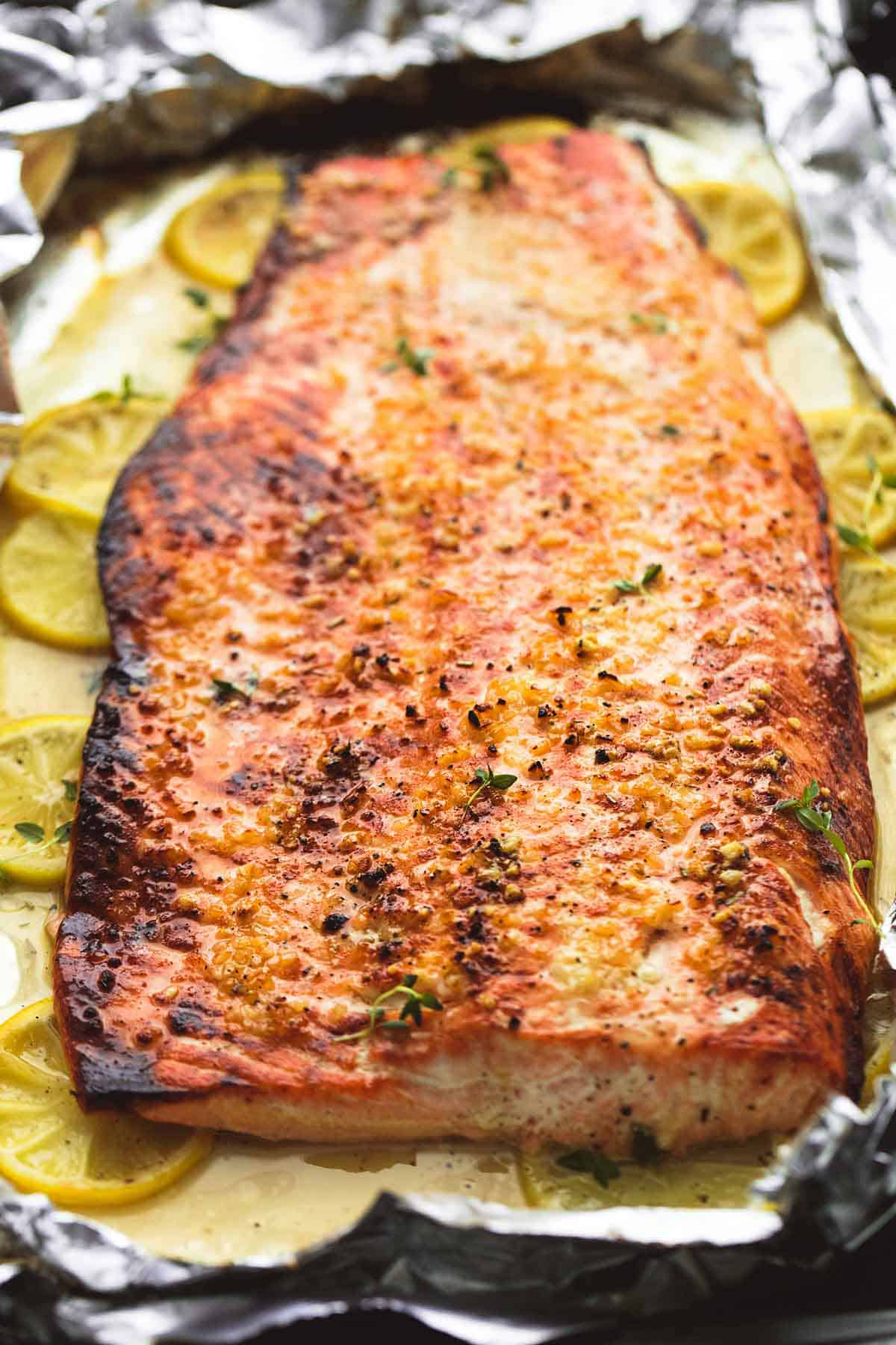 baked honey lemon garlic salmon in foil with lemon wheels underneath.