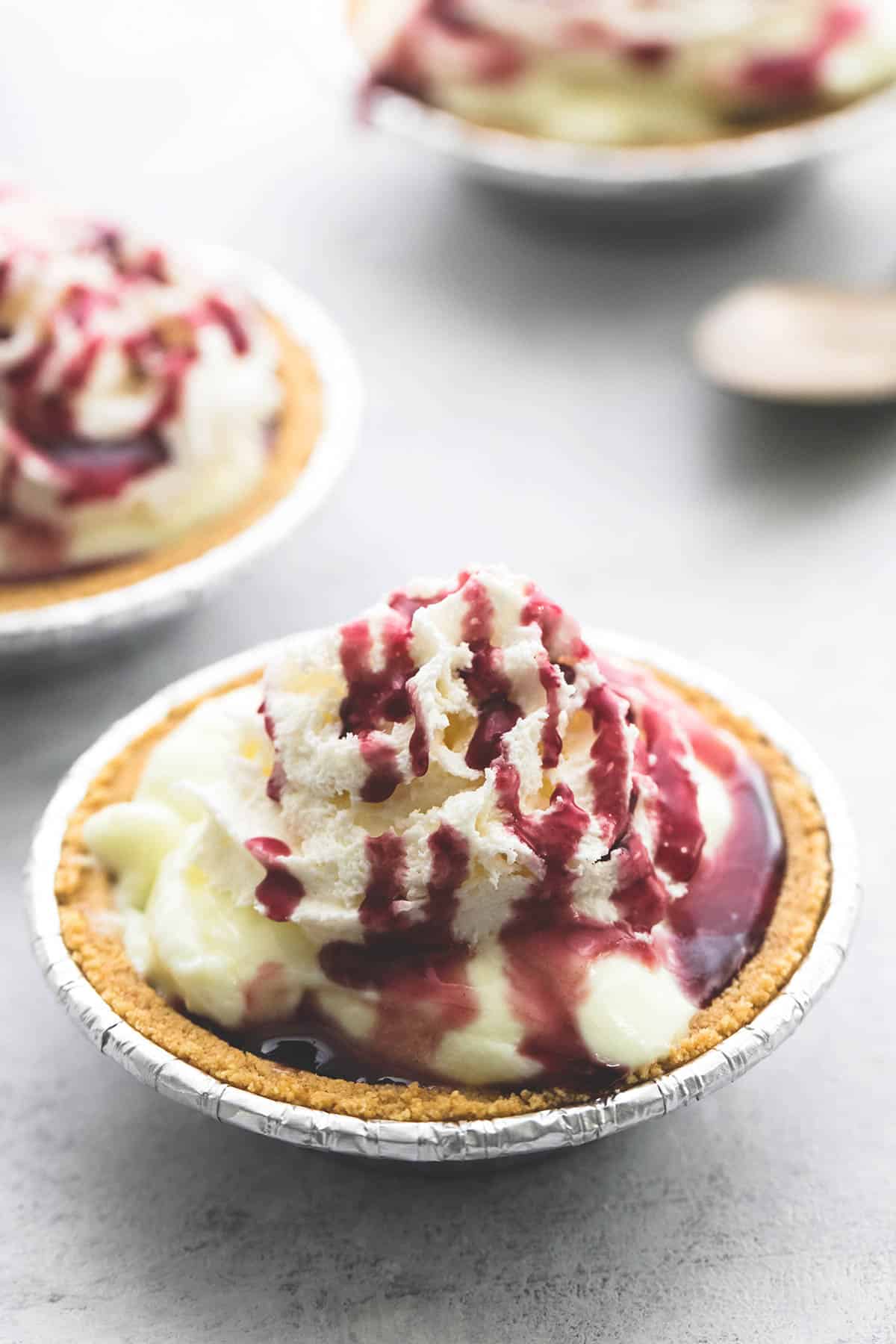 a lemon custard yogurt mini pie with more mini pies and a spoon faded in the background.