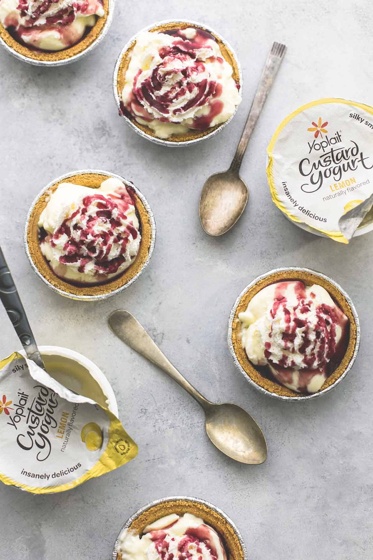 top view of lemon custard yogurt mini pies with yogurt containers and spoon with one yogurt container being opened with a spoon inside.