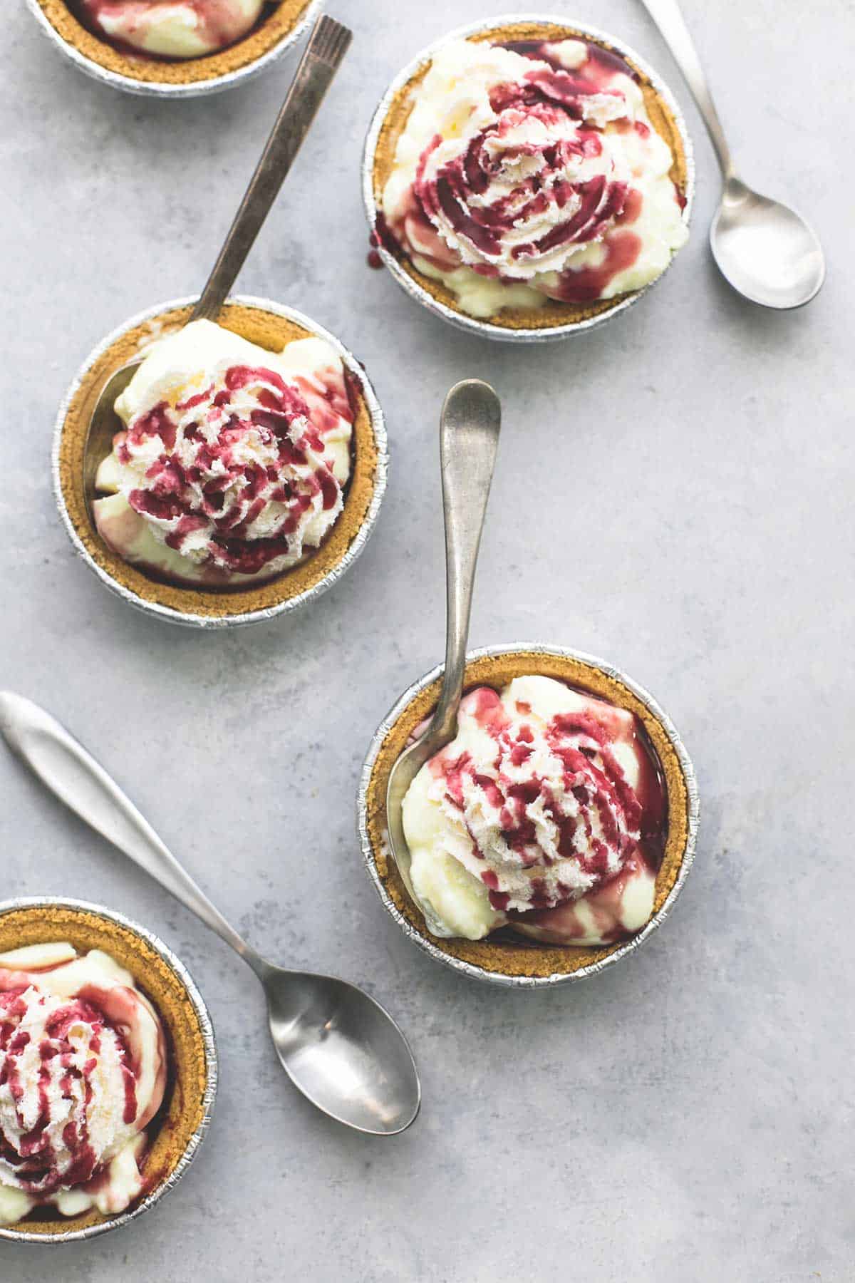 top view of lemon custard yogurt mini pies with some having spoons in them and others having spoons on the side.