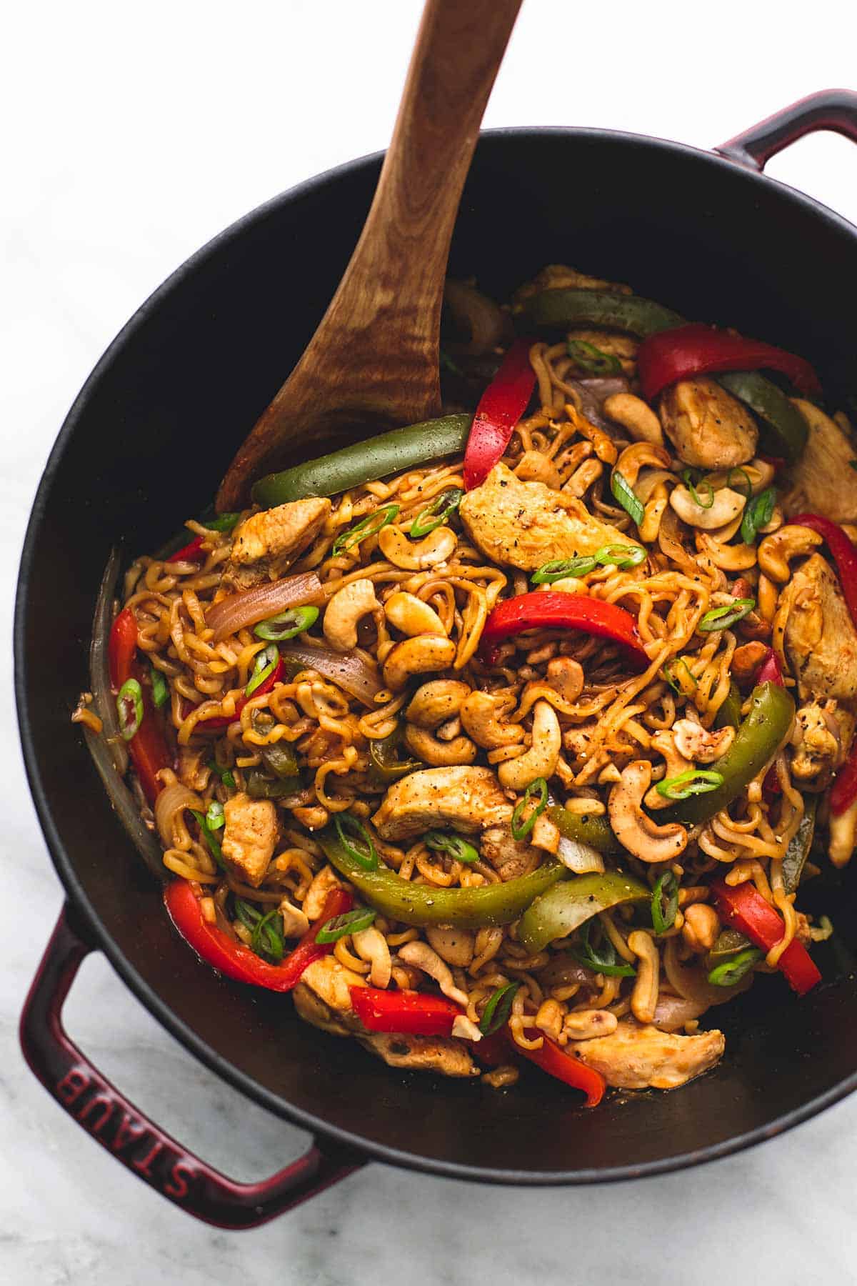 top view of cashew chicken ramen with a wooden serving spoon in a wok.