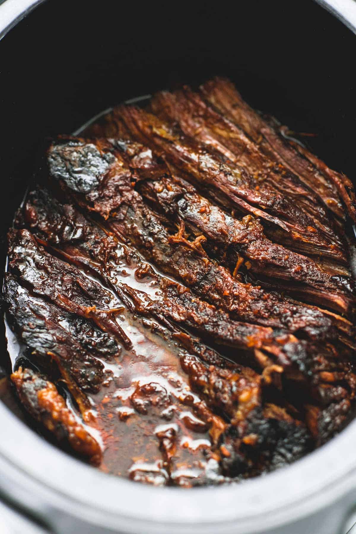 close up of slow cooker honey bbq beef brisket not shredded in a slow cooker.