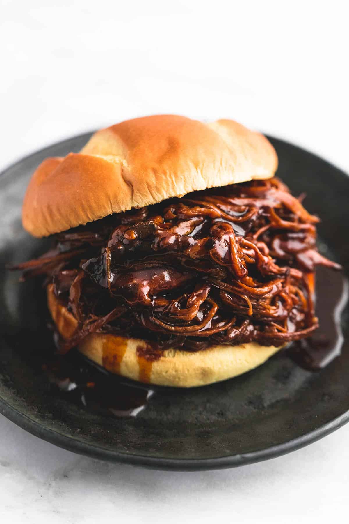 Slow Cooker Honey BBQ Beef Brisket | lecremedelacrumb.com a slow cooker honey bbq beef brisket sandwich on a plate.