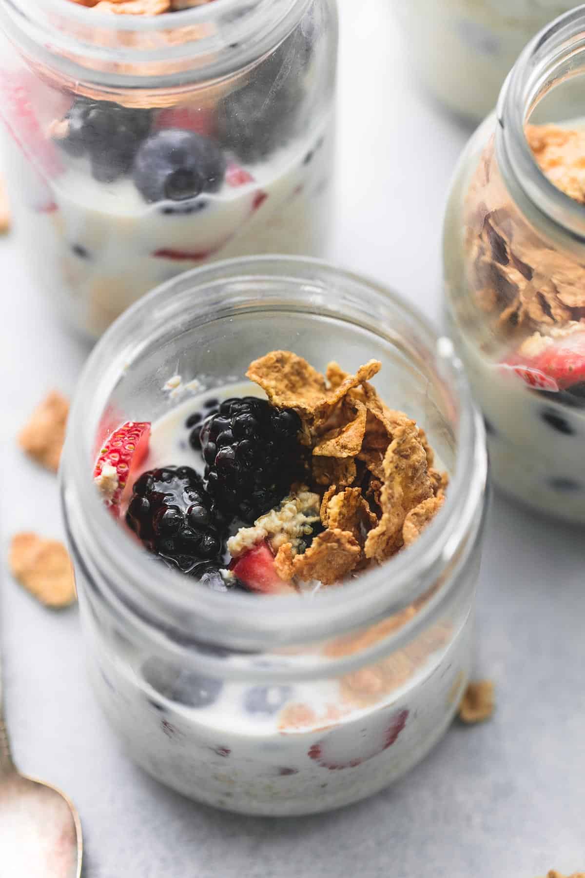 close up of berry crunch overnight oats in a jar with more jars of oats in the background.