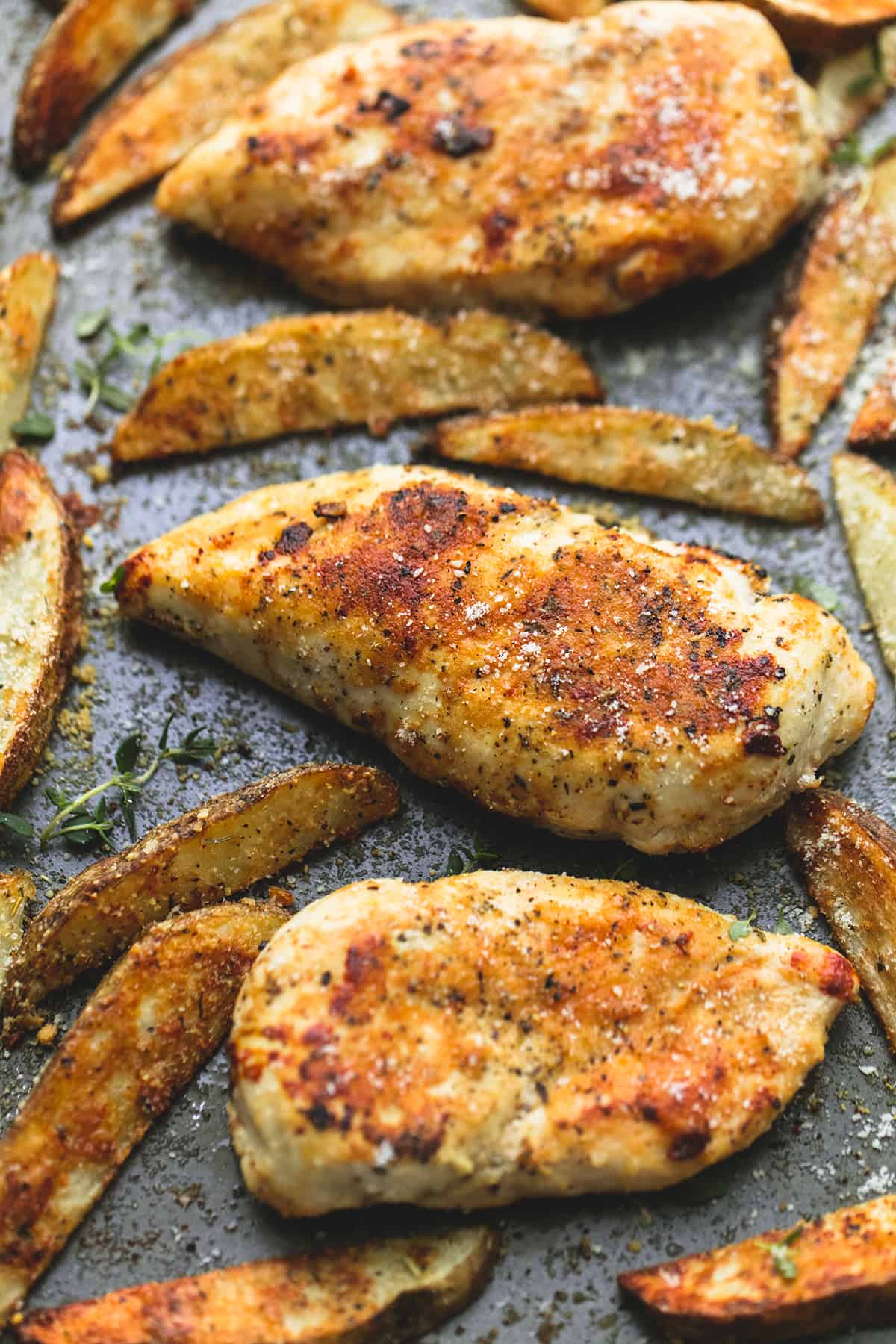 close up of garlic parmesan chicken & potatoes on a baking sheet.
