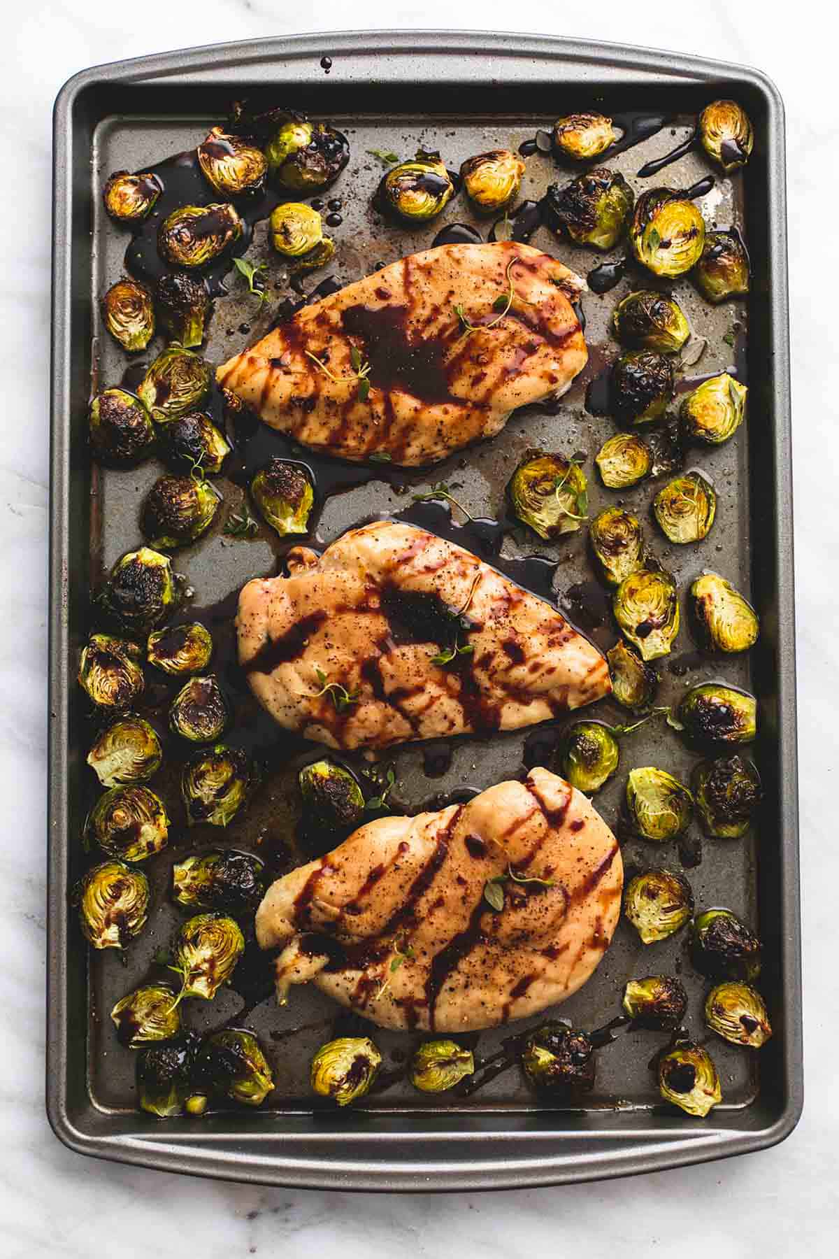 top view of honey balsamic chicken & brussels sprouts on a baking sheet.