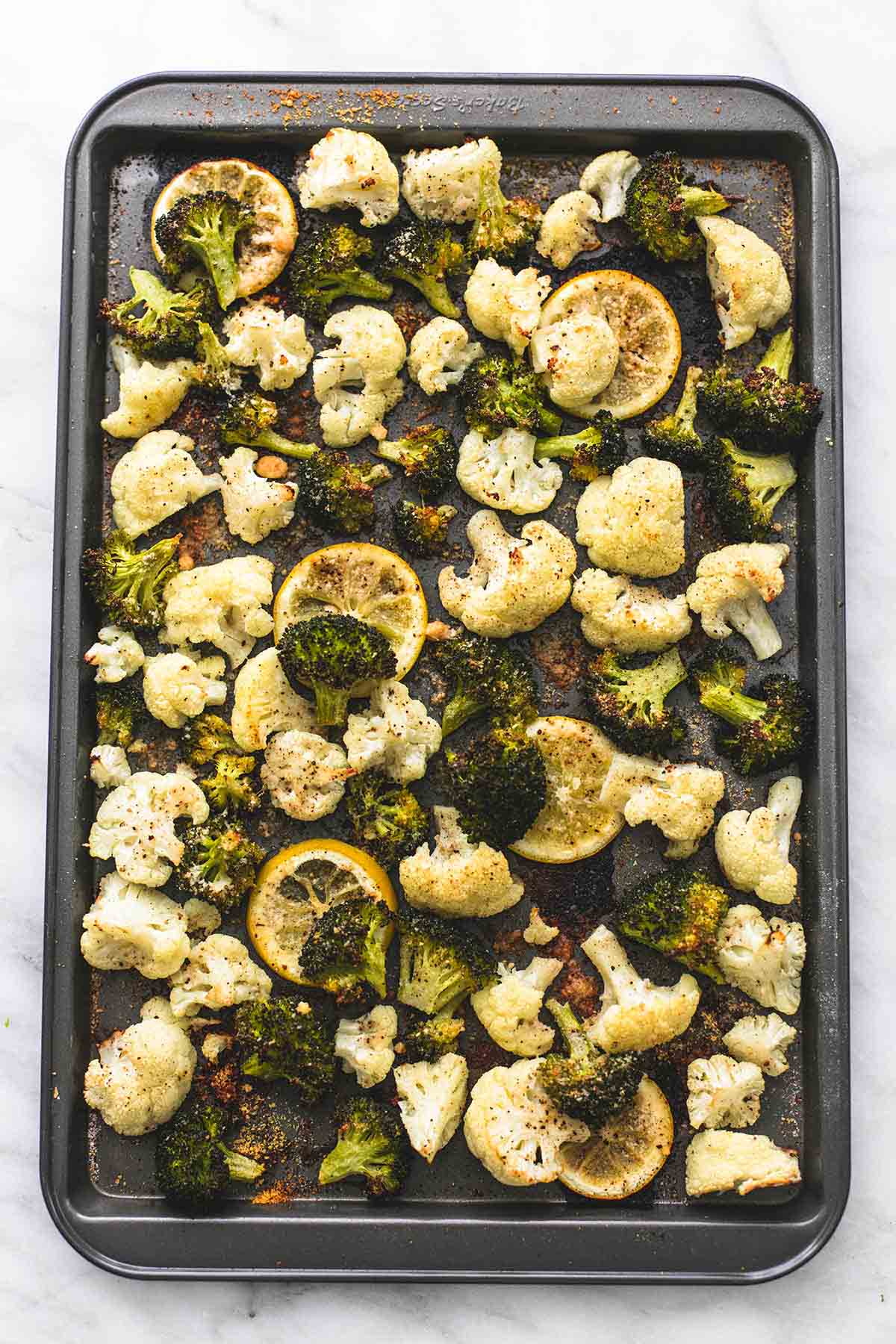 top view of roasted lemon garlic broccoli & cauliflower on a baking sheet.