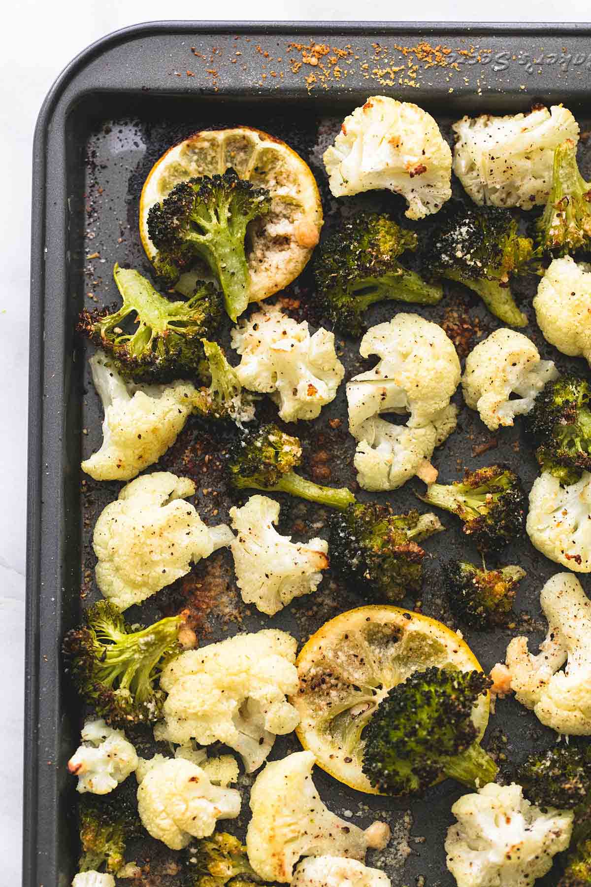 close up top view of roasted lemon garlic broccoli & cauliflower on a baking sheet.