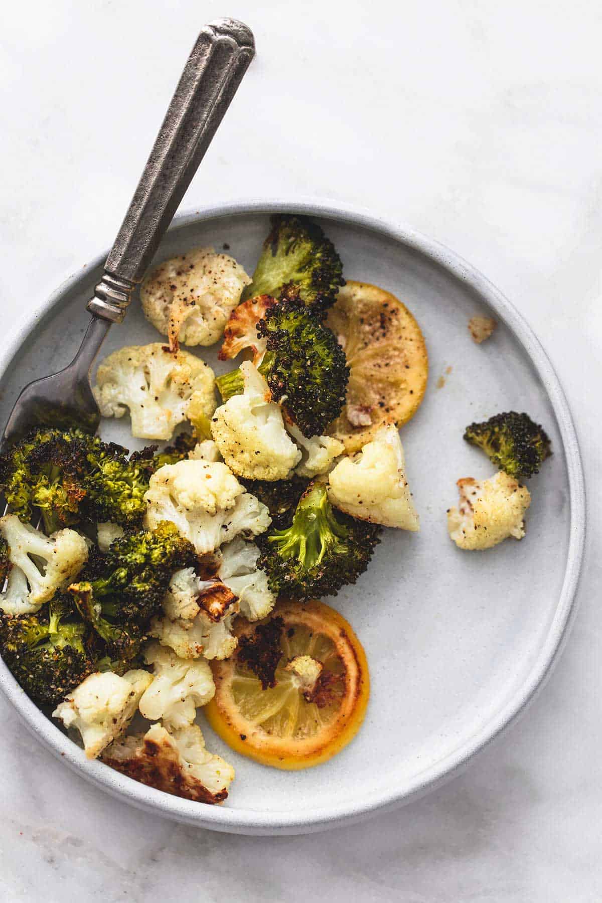 top view of roasted lemon garlic broccoli & cauliflower with a fork on a plate.