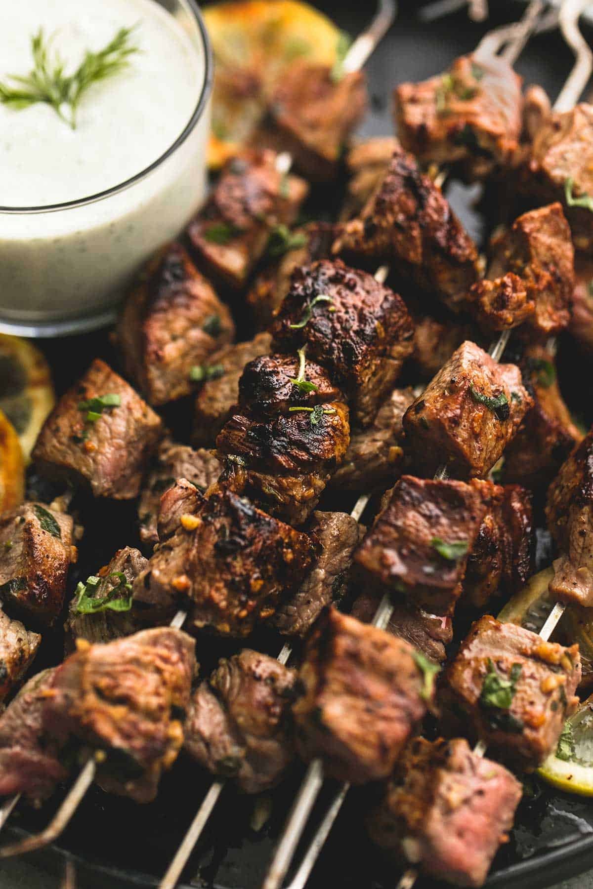 close up of beef Souvlaki kebabs with tzatziki sauce on a plate.